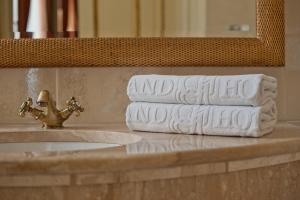 uma pilha de toalhas num balcão de casa de banho ao lado de um lavatório em Grand Hotel em Cracóvia