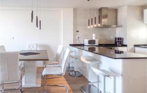 2 Bedroom Lovely Apartment In Orihuela Costa في Los Dolses: مطبخ مع طاولة وكراسي بيضاء في الغرفة