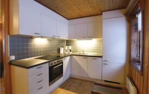 2 Bedroom Awesome Home In Sysslebck في Sysslebäck: مطبخ بدولاب بيضاء وفرن علوي موقد