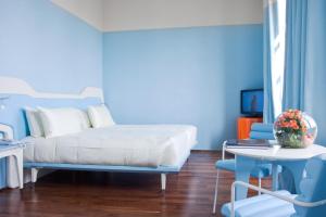 niebieska sypialnia z łóżkiem, stołem i krzesłami w obiekcie JR Hotels Bari Grande Albergo delle Nazioni w mieście Bari