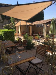 un patio extérieur avec des tables et un parasol dans l'établissement Le Cheval Blanc, à La Bastide-des-Jourdans