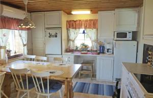 Nice Home In Malmkping With Kitchen في Malmköping: مطبخ مع طاولة وكراسي وثلاجة