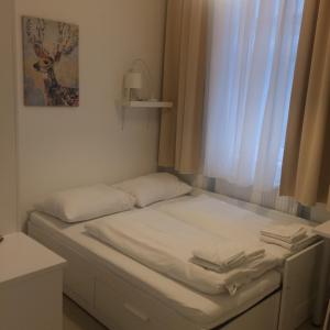 a white bed sitting in a room next to a window at CH-Vienna City Rooms in Vienna