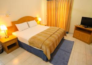 
a hotel room with a bed and a lamp at Al Shorouq Hotel Apartments in Muscat
