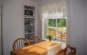 a dining room with a wooden table and a window at One-Bedroom Holiday Home In Gullabo in Gullabo