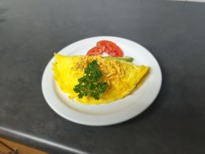 eine weiße Platte mit einem Omelett mit Tomaten und Käse in der Unterkunft Leach Lodge in Kuruman