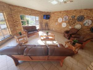 ein großes Wohnzimmer mit einem Sofa und Tischen in der Unterkunft Leach Lodge in Kuruman