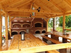 a wooden pavilion with a large wooden table and a brick oven at Casuta Din Padure in Drăguş