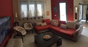 ein Wohnzimmer mit einem roten Sofa und Stühlen in der Unterkunft Ajmi Luxury Villa in Golem