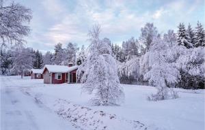 a red cabin in a snow covered forest with trees at 2 Bedroom Awesome Home In Sysslebck in Sysslebäck