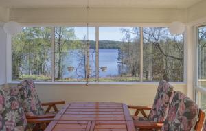 ein Esszimmer mit einem Tisch und Stühlen sowie einem großen Fenster in der Unterkunft Beautiful Home In Eksj With House Sea View in Hult
