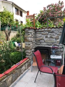 d'une terrasse avec une cheminée en pierre et un fauteuil rouge. dans l'établissement Lily 7, à Koper