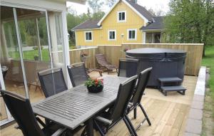 un patio con tavolo, sedie e vasca idromassaggio di Cozy Home In Oskarstrm With Kitchen a Karlstorp