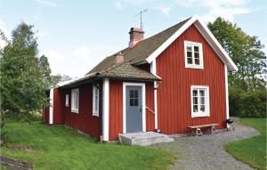 a red house with a bench in front of it at Amazing Home In Lammhult With Kitchen in Lammhult