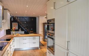 Gorgeous Home In Ystad With Kitchen في إيستاد: مطبخ بدولاب بيضاء وفرن علوي موقد