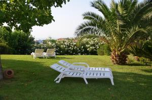 two white benches sitting in the grass in a park at Borgo Rosso Country House B&B in Sirolo