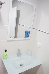 Baño blanco con lavabo y espejo en Hostal Goyesco Plaza en Plasencia