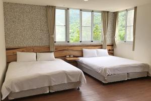 two beds in a room with two windows at Chihpen Lucky Hot Spring B&B in Wenquan