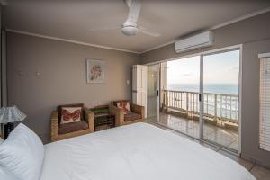 a bedroom with a bed and a balcony with the ocean at Sorgente 405 with inverter in Umdloti