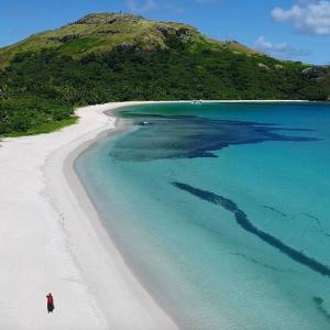 a person standing on a beach near the ocean at Malakati Village Beach House in Nacula Island