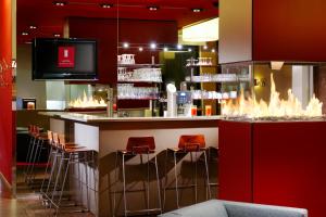 Eine Bar in einem Restaurant mit roten Stühlen und einem Fernseher in der Unterkunft Hotel Königstein in München