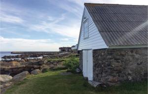 a stone building next to a stone wall and the ocean at Holiday Home Vanse Østhasselstrand Ii in Vanse