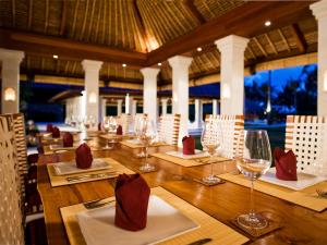 a restaurant with a long wooden table with wine glasses at Villa Sepoi Sepoi by Elite Havens in Tanjung