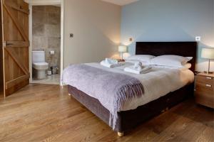 a bedroom with a large bed and a bathroom at The Threshing Barn in Pwllheli