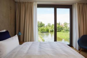 1 dormitorio con ventana grande con vistas al río en Sternen Bohlingen Aparthotel, en Singen