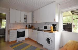 a kitchen with white cabinets and a washer and dryer at Awesome Home In Ed With 3 Bedrooms in Åsen