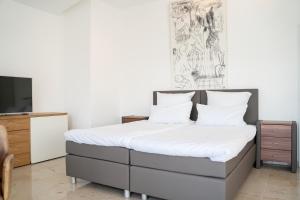 a bedroom with a bed with white sheets and a tv at Villa Sonne in Bodman-Ludwigshafen