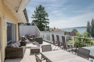 balcón con sillas, mesas y vistas al agua en Villa Sonne, en Bodman-Ludwigshafen