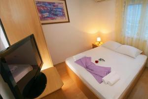 a small bedroom with a bed and a television at Hotel Amicus in Mostar