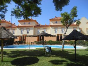 un complejo con piscina y sombrillas en Casa Playa Islantilla Golf, en Islantilla