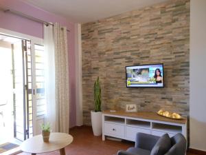 a living room with a tv on a brick wall at Casa Playa Islantilla Golf in Islantilla