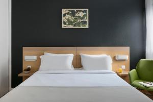 a bed with a white comforter and pillows at Citadines Austerlitz Paris in Paris