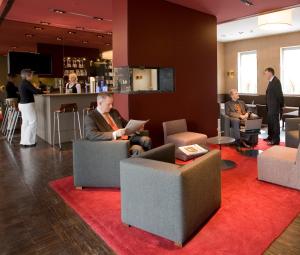 un grupo de personas sentadas en sillas en un vestíbulo en Hotel Königstein, en Múnich