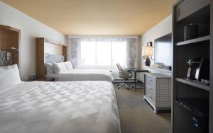Cette chambre comprend deux lits et un bureau. dans l'établissement Holiday Inn Montreal Longueuil, an IHG Hotel, à Longueuil