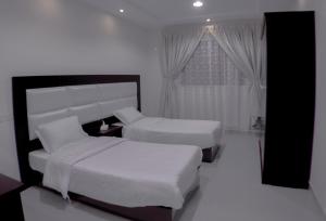 Una habitación de hotel con dos camas y una ventana. en روز الخيال للشقق المخدومة, en Hotat bani tamim