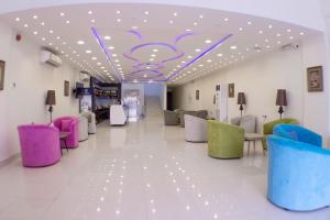 una sala de espera con sillas coloridas y techo en روز الخيال للشقق المخدومة, en Hotat bani tamim