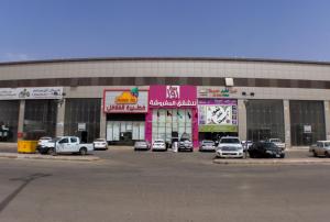 Un estacionamiento con autos estacionados frente a un edificio. en روز الخيال للشقق المخدومة, en Hotat bani tamim