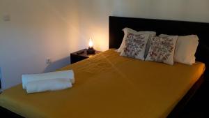 Un dormitorio con una cama amarilla y una lámpara en una mesa en Palheiros de Mira, en Praia de Mira