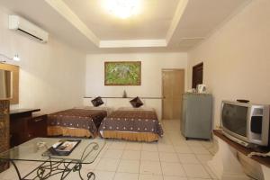 a hotel room with two beds and a tv at Alit Beach Resort and Villas in Sanur