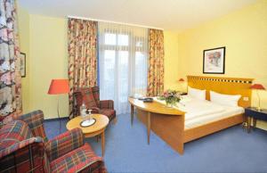 ein Hotelzimmer mit einem Bett, einem Tisch und Stühlen in der Unterkunft Hotel am Kurpark in Schönebeck