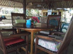 a wooden table and chairs with a vase of flowers on it at Sunset Cottages in Hitokalak