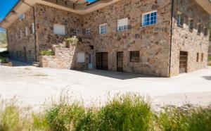 - un grand bâtiment en pierre avec des fenêtres et une cour dans l'établissement Hostal La Majada, à Castellanos