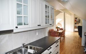a kitchen with white cabinets and a sink and a table at Cozy Apartment In Fitjar in Fitjar