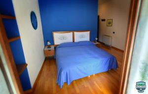 a blue bedroom with a bed and a wooden floor at Cascina Roland in Villar Focchiardo