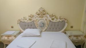 a white bed with an ornate headboard in a bedroom at AL SHEIKH 5 BEDROOM LUXURY APARTMENT 1 in Yerevan