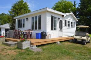 ein kleines weißes, winziges Haus mit einer Holzterrasse in der Unterkunft Doran Bay Resort in Iroquois